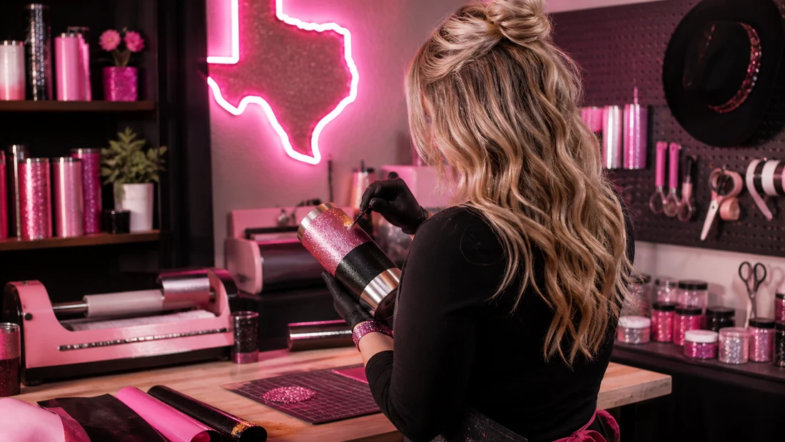 Sassy Texan Designs maker hand-finishing a custom pink glitter tumbler in her studio.